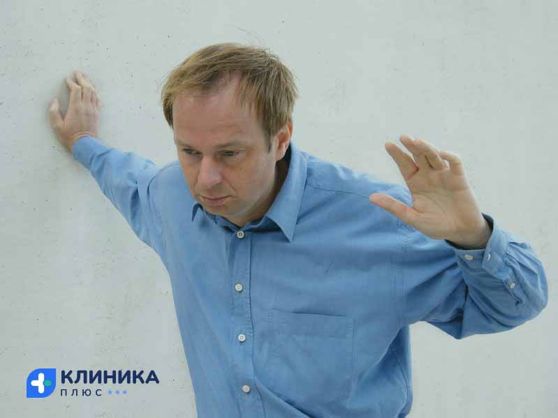Мужчина держится за стену