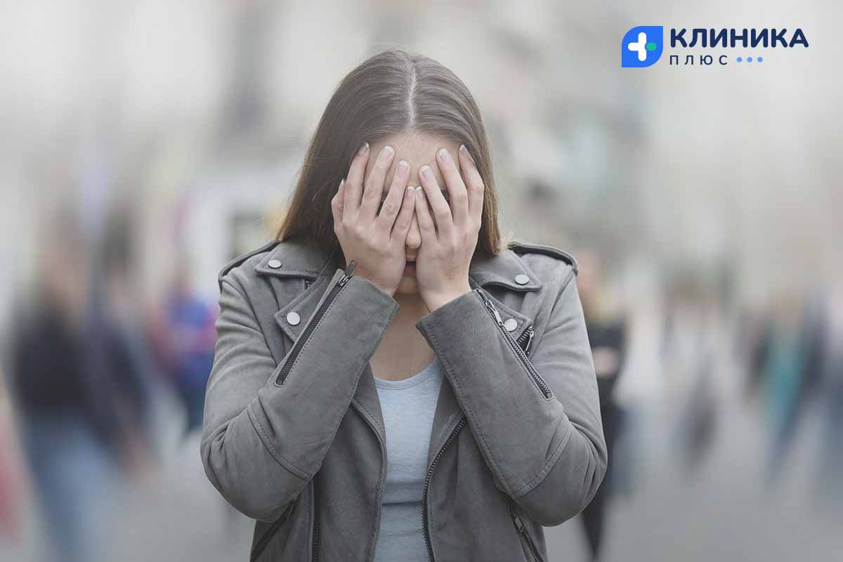 Женщина закрывает лицо руками на улице
