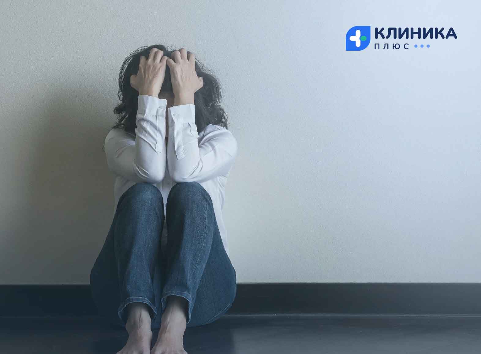 Женщина сидит на полу, закрыв лицо руками