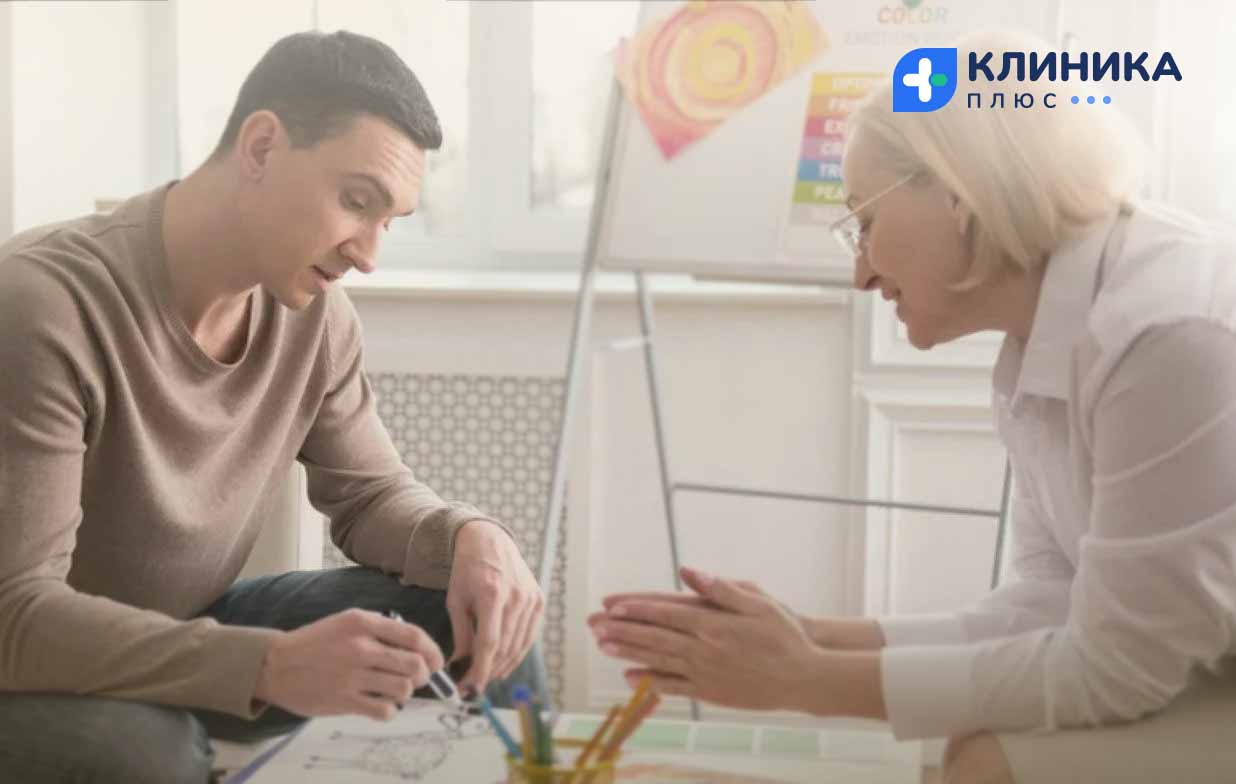 Мужчина рисует под присмотром психолога